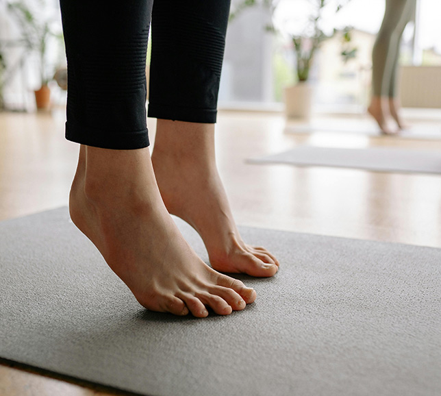 A close up of feet standing on tip toes on an exercise mat