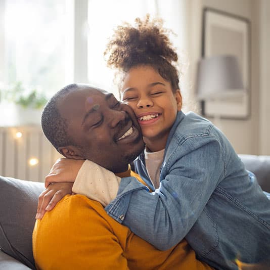 Father and daughter hugging and smiling on a sofa