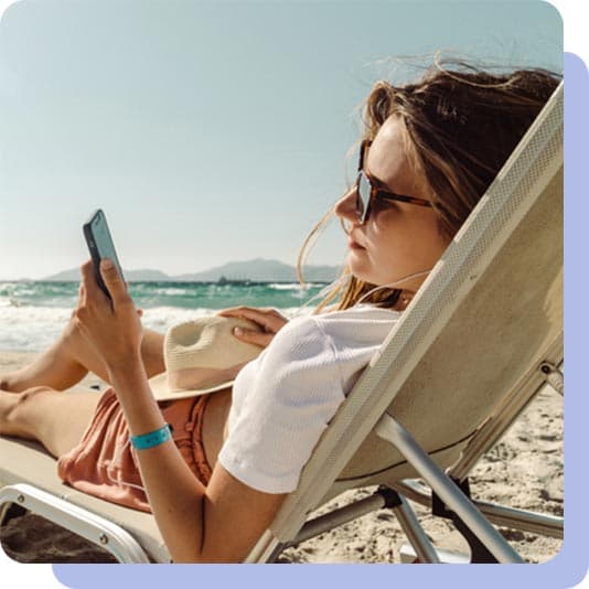 Lady with a smartphone on a sun lounger at the beach