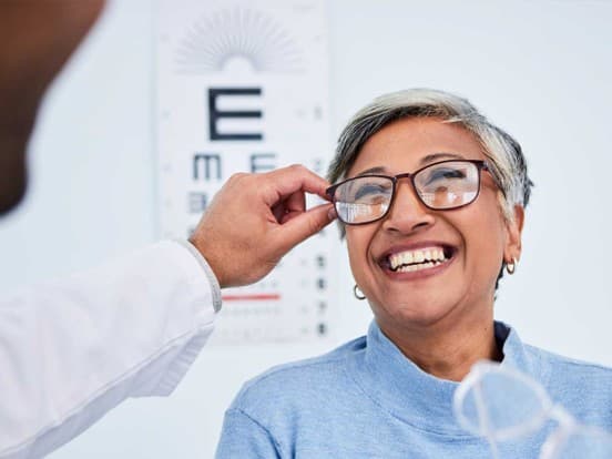 Lady trying on glasses in opticians