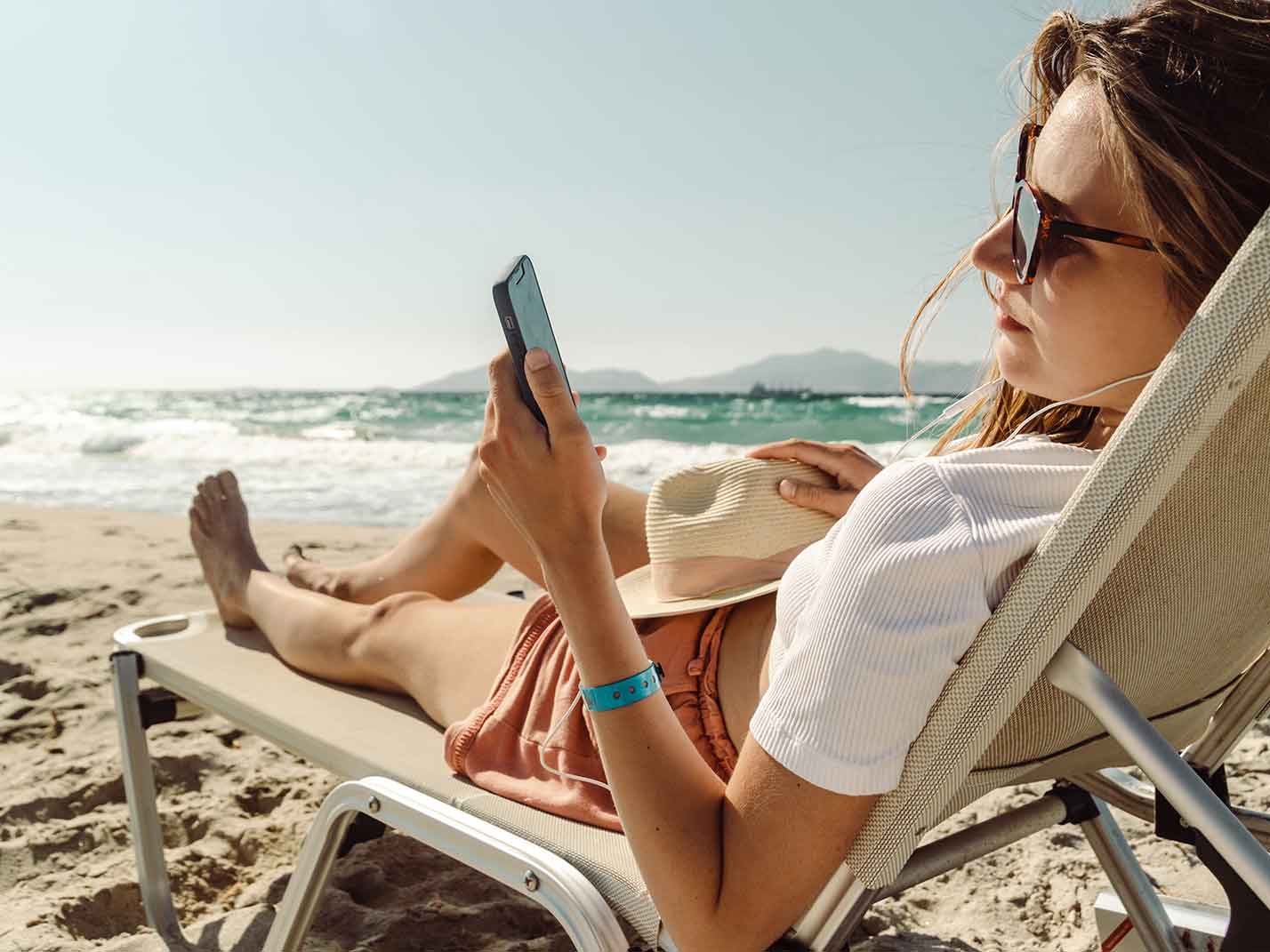 Lady using phone lying on beach