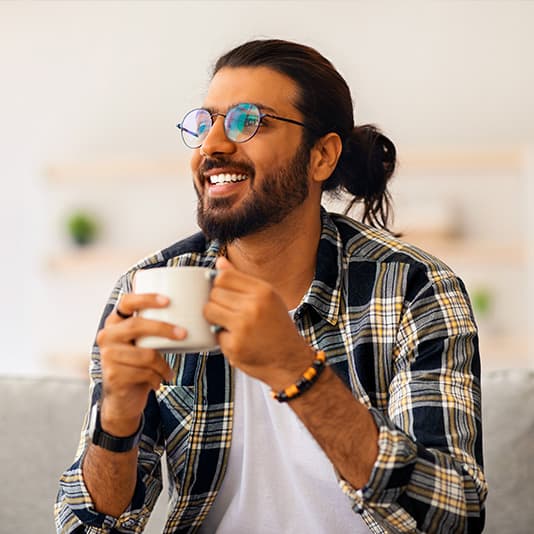 Smiling man on sofa with mug of tea