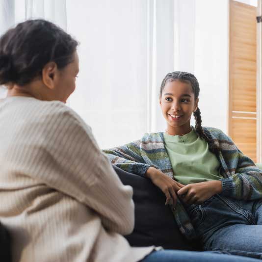 Mother and daughter having chat on sofa