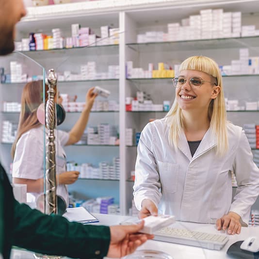 Pharmacist handing prescription to customer