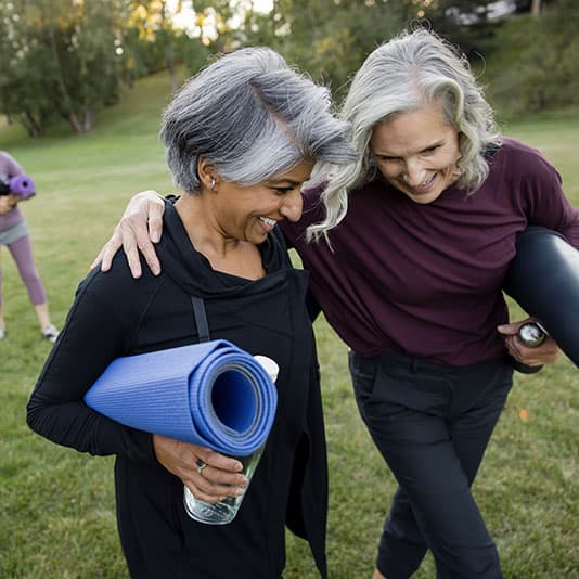 Two women smiling after an outdoor yoga class